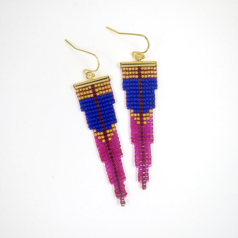 May include: A pair of gold dangle earrings with pink, blue, and gold geometric bead patterns.
