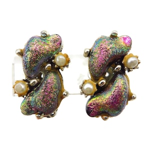 May include: A pair of clip-on earrings featuring two iridescent, textured, kidney-shaped components with a metallic rainbow finish. Each earring is accented with two small, round, white faux pearls set in a yellow-toned base with silver-colored metal details.