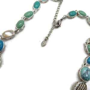 A close-up of the silver-tone extender chain and clasp of the necklace, with a small oval tag reading "MONET" visible.