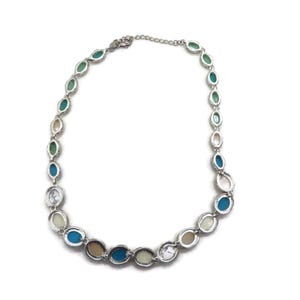 The back of a silver-tone necklace with alternating oval and round beads in turquoise, cream, and brown, laid flat in a full circle on a white background.