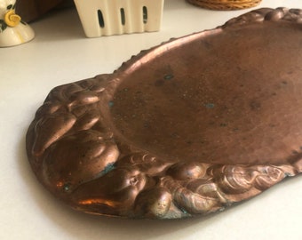 May include: A vintage copper serving tray with a hammered finish and an ornate design of raised fruit around the edge.