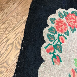 Puede incluir: Una alfombra vintage con un borde negro y un centro blanco con un dise&ntilde;o floral con flores rosas y verdes.
