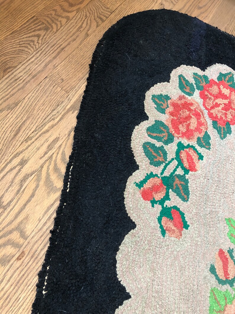Puede incluir: Una alfombra vintage con un borde negro y un centro blanco con un dise&ntilde;o floral con flores rosas y verdes.