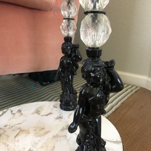 May include: A round marble table with two black cherub-shaped legs. Each leg is topped with three clear crystal balls.