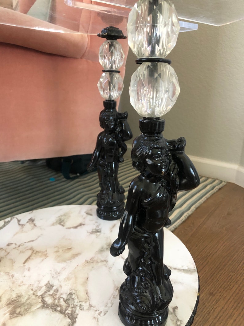 May include: A round marble table with two black cherub-shaped legs. Each leg is topped with three clear crystal balls.