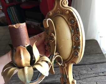 May include: A vintage wall sconce with a floral design. The sconce is made of metal and has a gold finish. It features a single light bulb socket and a decorative floral design.