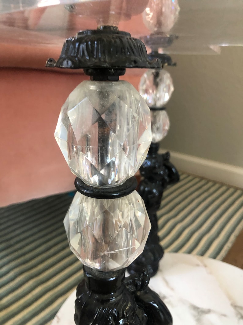 May include: Close-up of a black and clear glass table base with a crystal ball design. The base is made of metal and has a decorative design. The table top is not visible in the image.