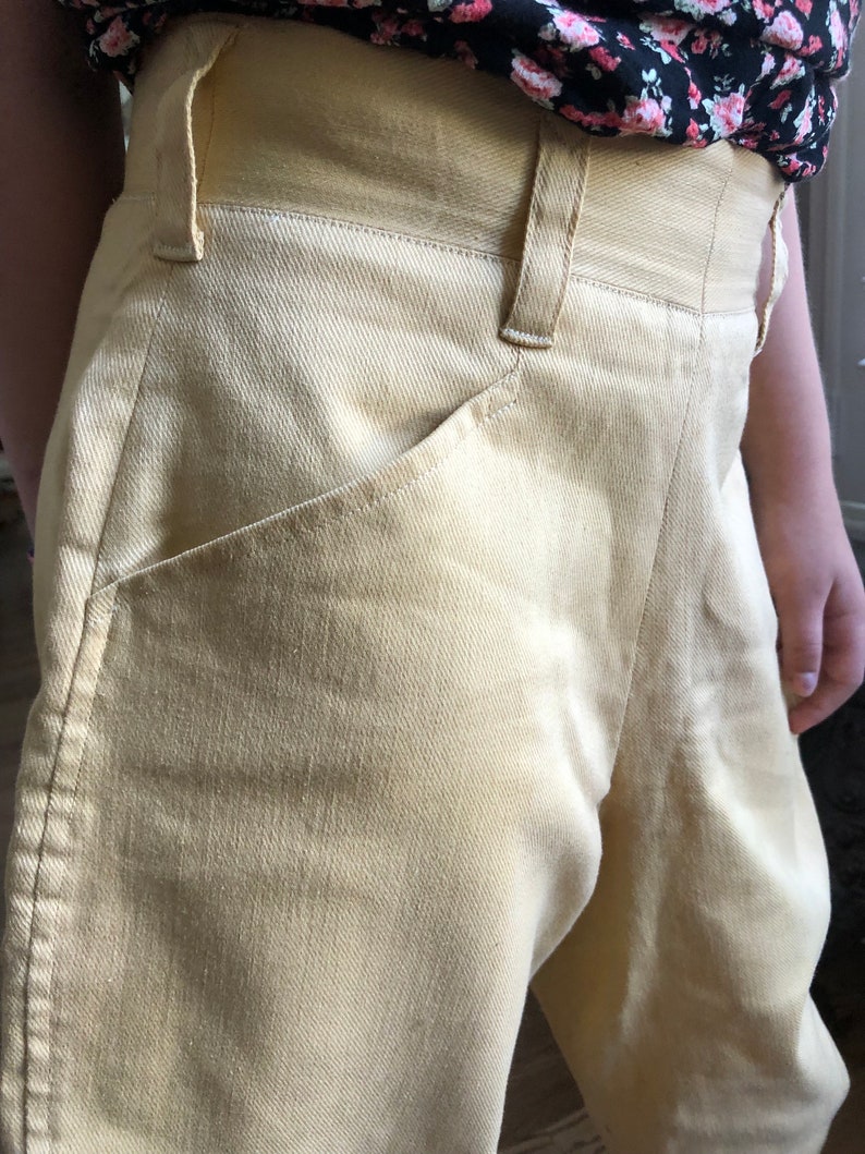 Op de afbeelding: Een lichtgele broek met hoge taille en een voorzak.
