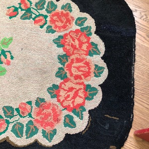 Puede incluir: Una alfombra vintage con fondo negro y centro blanco con un dise&ntilde;o floral de rosas rojas y hojas verdes.
