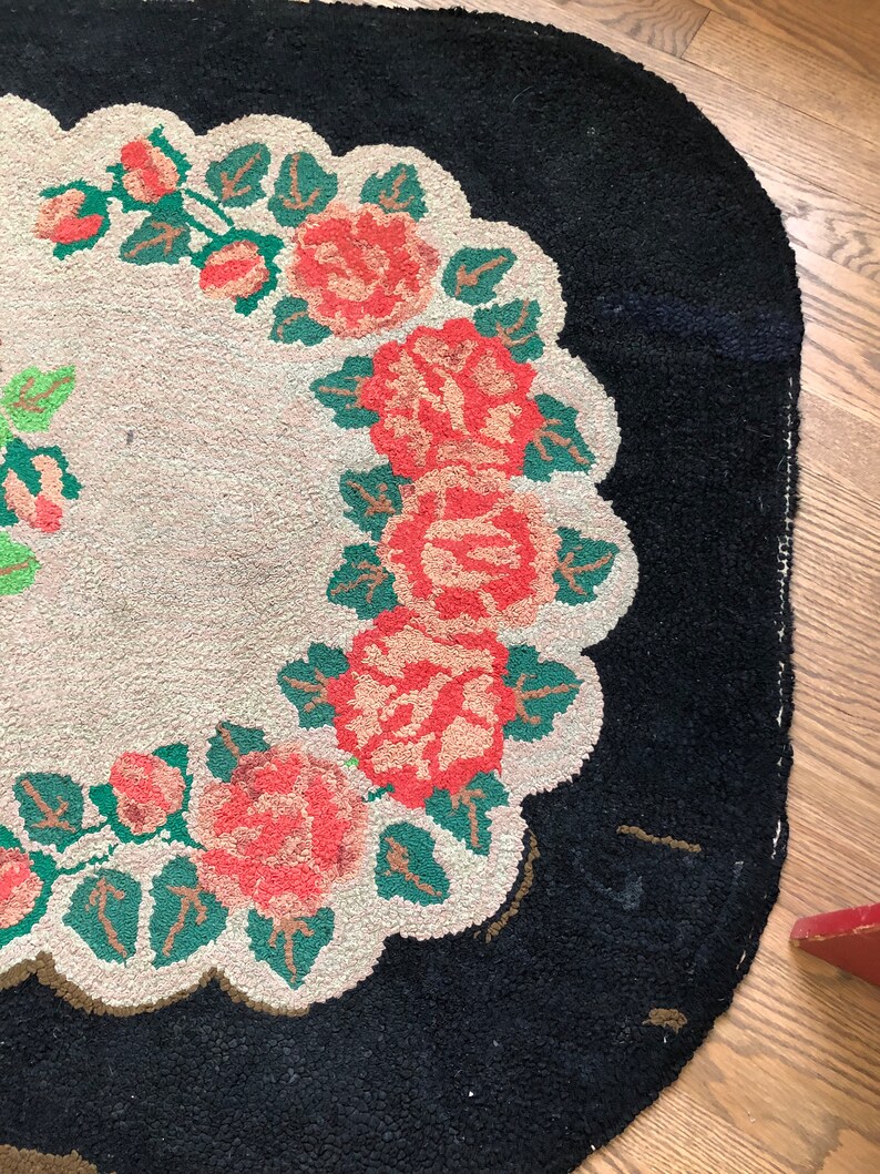 Puede incluir: Una alfombra vintage con fondo negro y centro blanco con un dise&ntilde;o floral de rosas rojas y hojas verdes.