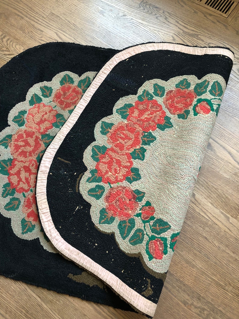 Puede incluir: Una alfombra negra y blanca con un borde rosa. La alfombra tiene un dise&ntilde;o floral con rosas rojas y hojas verdes.