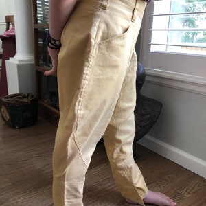 Op de afbeelding: Een lichtgele broek met een split aan de onderkant van elk been. De broek heeft een hoge taille en een ontspannen pasvorm.