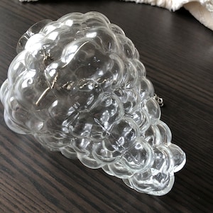 May include: A clear glass grape-shaped pendant light fixture with a chain.