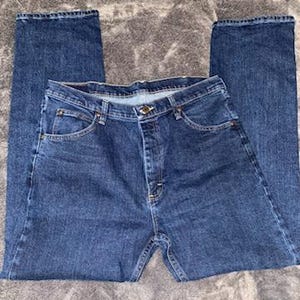May include: A pair of blue denim jeans with a classic five-pocket design. The jeans have a button and zipper closure, belt loops, and a straight leg cut. The denim has a medium wash with subtle fading.