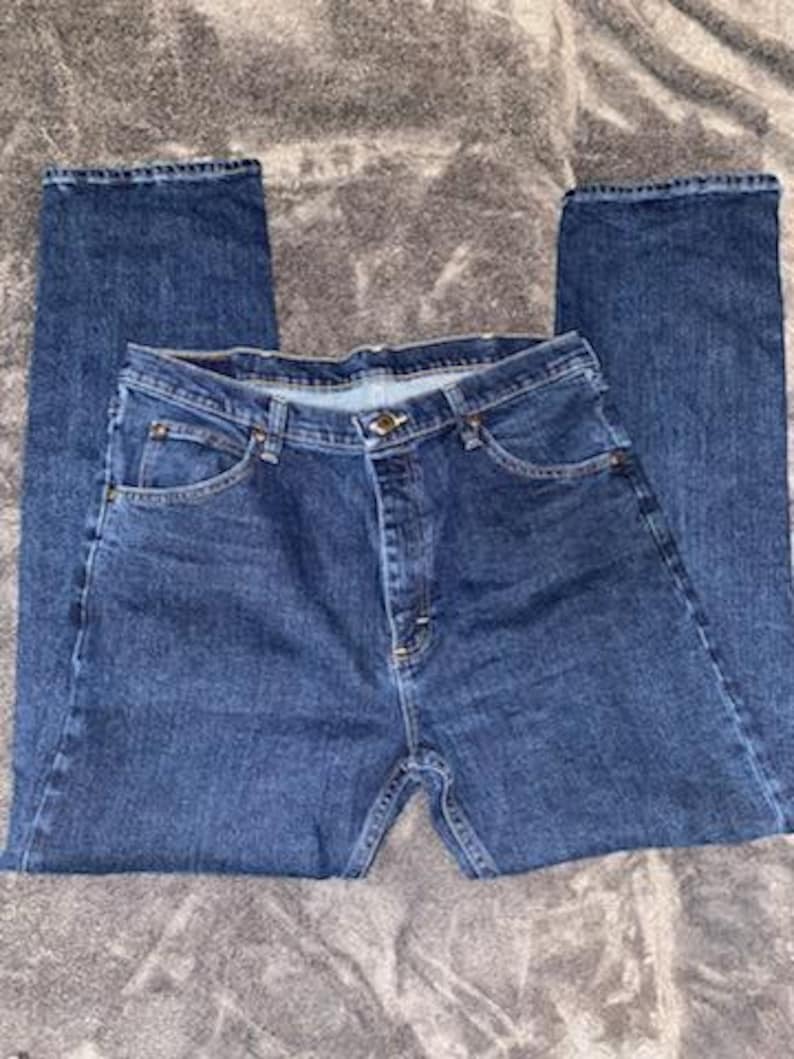 May include: A pair of blue denim jeans with a classic five-pocket design. The jeans have a button and zipper closure, belt loops, and a straight leg cut. The denim has a medium wash with subtle fading.