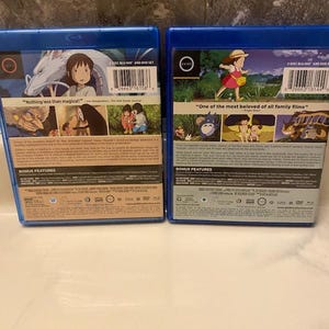 May include: Two blue Blu-ray and DVD sets. One features a girl and a dragon with the text "Nothing less than magical!". The other shows a girl in a field with the text "One of the most beloved of all family films".