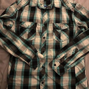 May include: A long-sleeved plaid shirt in shades of teal, black, and white. The shirt has two chest pockets and buttoned cuffs. The brand name "Helix" is visible on the label.