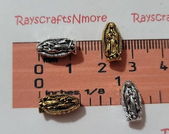 Puede incluir: Cuatro abalorios de metal plateado y dorado con una imagen de la Virgen María. Los abalorios miden aproximadamente 2,5 cm de largo y se muestran en una regla.