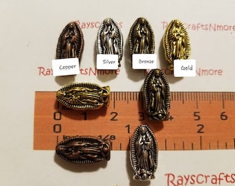 Peut inclure: Assortiment de sept breloques en métal représentant une image de la Vierge Marie. Les breloques sont en différentes finitions : cuivre, argent, bronze et or. Les breloques sont présentées sur une règle graduée en pouces.