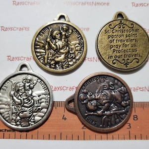 May include: Four Saint Christopher medallions with different finishes. Two are gold-toned, one is silver-toned, and one is a mix of copper and silver tones. The medallions feature an image of Saint Christopher carrying a child. One medallion has the inscription "St. Christopher patron saint of travellers, pray for us. Protect us in our travels."