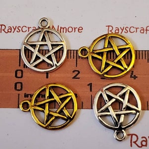 Peut inclure: Quatre breloques pentagrammes argentées et dorées avec une boucle pour accrocher. Les breloques sont sur une règle graduée en centimètres.