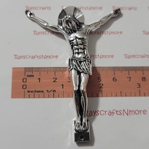 Peut inclure: Figurines en métal argenté d'une figure religieuse avec les bras tendus. La figurine mesure environ 12,7 cm de haut et est posée sur une petite base.
