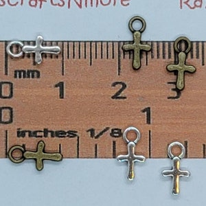 Puede incluir: Seis pequeños amuletos de metal en forma de cruz en acabados de oro antiguo y plata. Los amuletos miden aproximadamente 1 pulgada de largo y tienen un bucle en la parte superior para sujetarlos a joyas u otras manualidades.