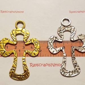 Puede incluir: Dos cruces decorativas de metal, una dorada y otra plateada, con superficie texturizada. Las cruces miden aproximadamente 7,6 cm de largo. El texto "RaysCraftsNmore" es visible en la imagen.