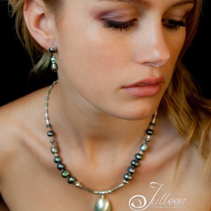Peut inclure: Une femme portant un collier avec un pendentif en argent et des perles vert foncé. Le pendentif est de forme ovale et a une surface lisse et polie. Le collier est fait d'une chaîne en argent et est accentué de petites perles vert foncé.