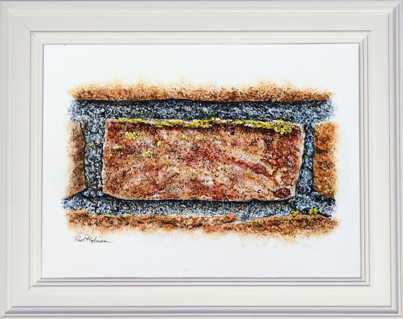 The finished brick painting in a white frame. The study focuses on a single brick with the mortar and the suggestion of other bricks around the edge. The brick is terracotta, with grey mortar and bits of yellow lichen in places too.