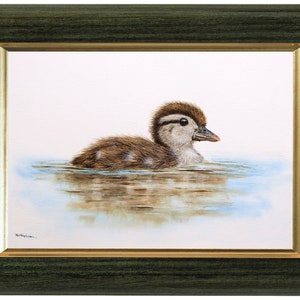 Wood duckling painting in a green frame with a gold inner trim