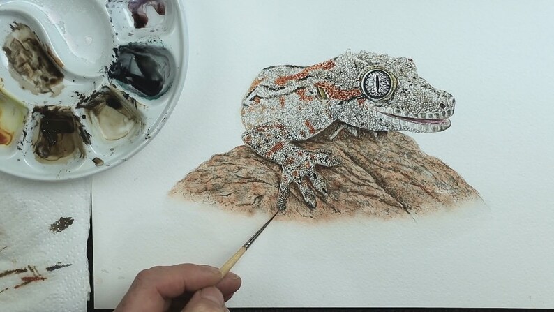 Paul is applying some basic details to a rock that the reptile is sitting on.  The rock is a warm brown, with greys and oranges mingled in.