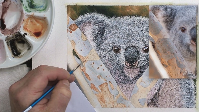 The Koala is fully painted in this photo, and Paul's hand with a small brush is shown over an area of the branch which he is beginning to paint.  This has grey peeling bark.