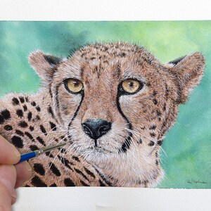 May include: A watercolour painting of a cheetah against a green background. The cheetah is looking directly at the viewer with its mouth closed. The cheetah's fur is a mix of brown, black, and white. The cheetah's eyes are brown.