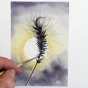 A silhouette of a grass seed head being painted by Paul against the background of the sun in a dark mauve coloured sky.  The seed head has lots of wispy hairs surrounding it, and creating a stunning effect against the background