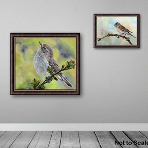 The chiffchaff painting in a dark frame is shown displayed on a grey painted wall.  Alongside is a smaller painting of a Brambling, in the same style frame.  Below is a grey wood panelled floor and the words 'not to scale'.