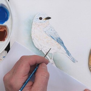 A screenshot from the painting, showing the completed eye and beak, and Paul in the process of over-painting his pencil outline of the bird with watercolor.