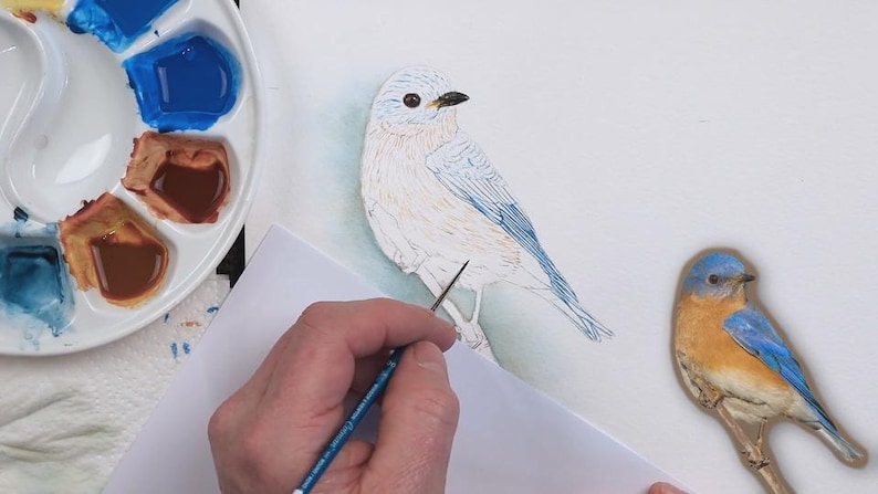 A screenshot from the painting, showing the completed eye and beak, and Paul in the process of over-painting his pencil outline of the bird with watercolor.