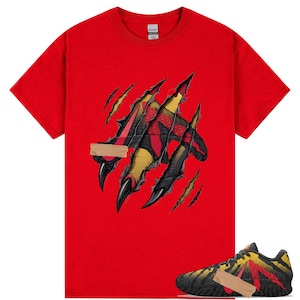 以下が含まれることがあります： 赤いTシャツと爪痕のデザイン、お揃いのスニーカー。爪痕は黄色、黒、赤のパターンを明らかにします。スニーカーも同様のデザインで、黒いソールと赤いアクセントがあります。