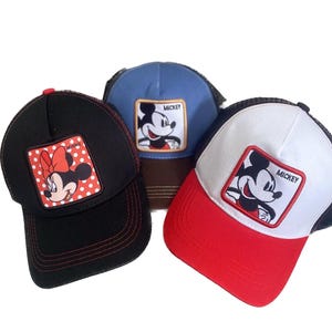 May include: Three baseball caps with cartoon character patches. One black cap features Minnie Mouse, another blue cap has Mickey Mouse, and a third cap is white and red with Mickey Mouse. All caps have a mesh back.