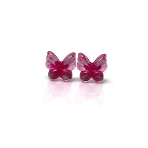 May include: A pair of magenta butterfly-shaped stud earrings. The earrings have a translucent appearance with a hint of silver detailing on the wings. The earrings are set against a white background.
