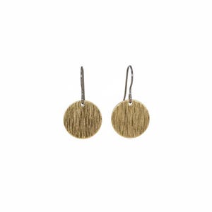 May include: A pair of gold-colored disc earrings with a textured, vertical-line pattern. The earrings have a simple hook design and are set against a white background. The earrings are a simple, yet elegant accessory.