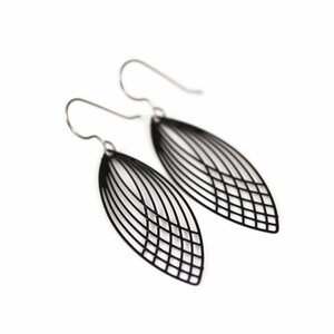 May include: A pair of black, openwork leaf-shaped earrings with silver-colored ear wires. The earrings have a delicate, geometric design, with thin lines creating the leaf shape. The earrings are displayed against a white background.