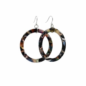 May include: A pair of large hoop earrings with a marbled pattern in shades of brown, black, green, and purple. The earrings have silver-coloured fish hook closures. The hoops are circular in shape.
