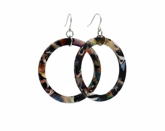 May include: A pair of large hoop earrings with a marbled pattern in shades of brown, black, green, and purple. The earrings have silver-colored fish hook closures. The hoops are circular in shape.