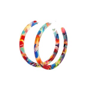 Peut inclure: Une paire de boucles d'oreilles créoles colorées. Les boucles d'oreilles présentent un motif vibrant de rouge, orange, jaune, bleu et vert. Les créoles sont faites d'un matériau brillant sur fond blanc.
