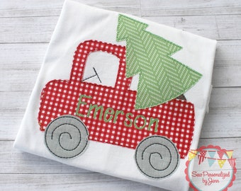 May include: Red and white gingham truck carrying a green Christmas tree with the name "Emerson" embroidered on the side.