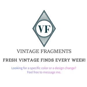 Pu&ograve; includere: Sfondo bianco con un logo a forma di diamante verde acqua contenente le lettere "VF" all'interno di un cerchio. Sotto il logo, il testo recita "VINTAGE FRAGMENTS" e "FRESH VINTAGE FINDS EVERY WEEK!"