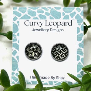 Op de afbeelding: Een paar ronde oorstekers met een zwart-wit geometrisch patroon. De oorbellen worden gepresenteerd op een witte kaart met de tekst "Curvy Leopard Jewellery Designs" en "Hand made By Shaz".