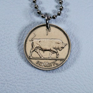 May include: A silver chain necklace with a silver pendant featuring a bull on one side and the text "1 scúnt" on the other side.